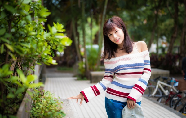 Красивая азиатка в полосатом свитере в парке