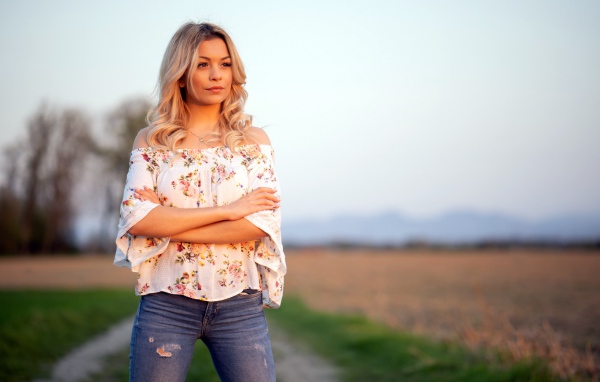 Красивая девушка блондинка в джинсах в поле