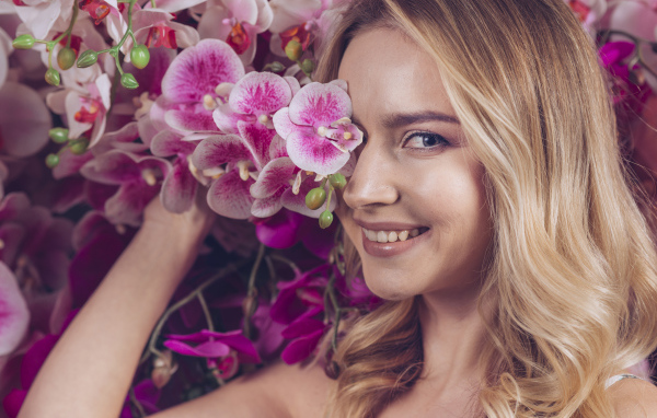 Красивая девушка блондинка с цветами орхидеи