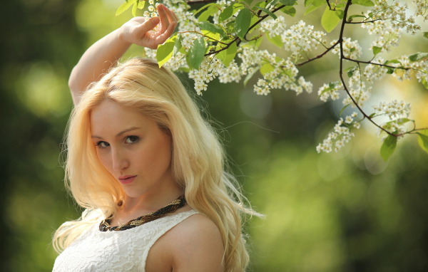 Красивая блондинка у ветки с белыми цветами