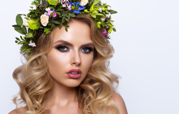 Красивая блондинка с венком из живых цветов на белом фоне