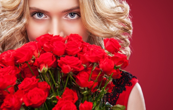Красивая голубоглазая блондинка с букетом красных роз 