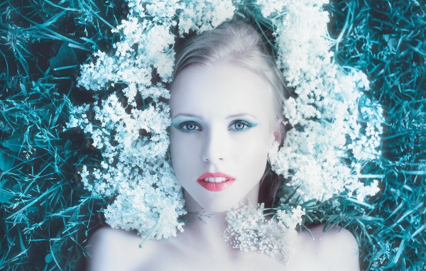 Красивая голубоглазая девушка на траве с белыми цветами