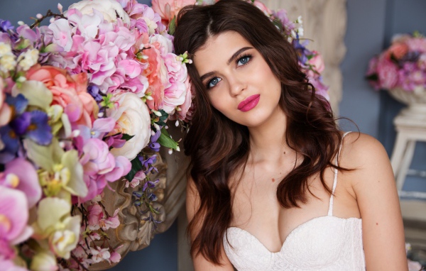 Красивая голубоглазая девушка стоит у цветов