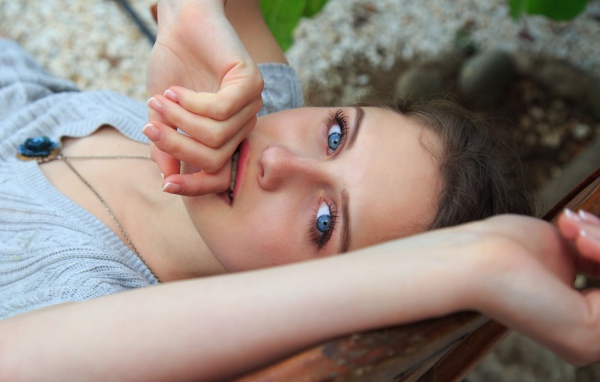 Красивая голубоглазая девушка с рукой у рта