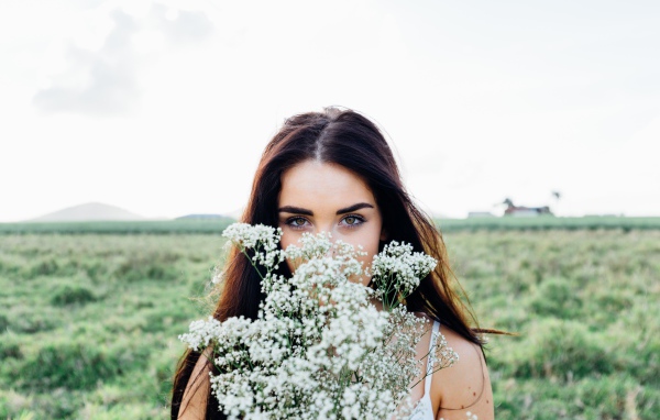 Красивая кареглазая девушка с букетом белых полевых цветов 