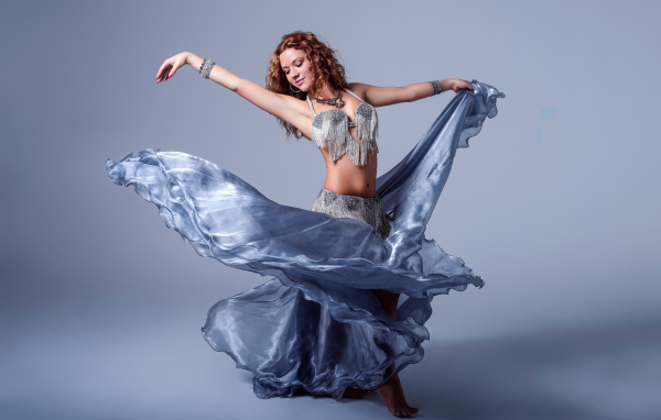 Красивая девушка в платье для танцев на сером фоне