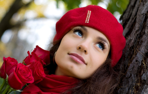 Красивая девушка в красном берете с букетом роз у дерева