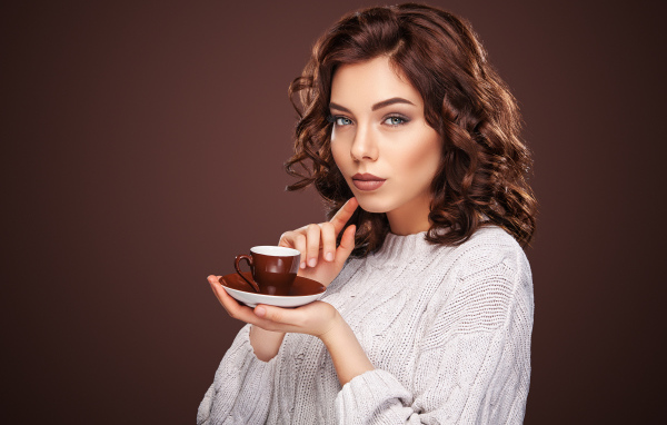 Красивая девушка в белом свитере с чашкой кофе