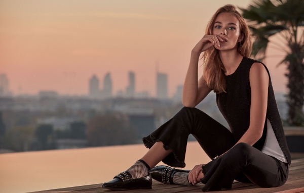 Красивая девушка в черном сидит  на мосту 