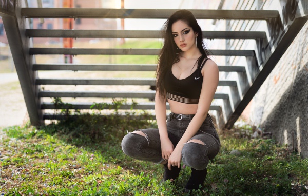 Красивая девушка сидит под лестницей 