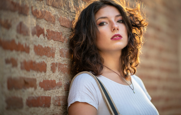 Красивая девушка стоит у стены 