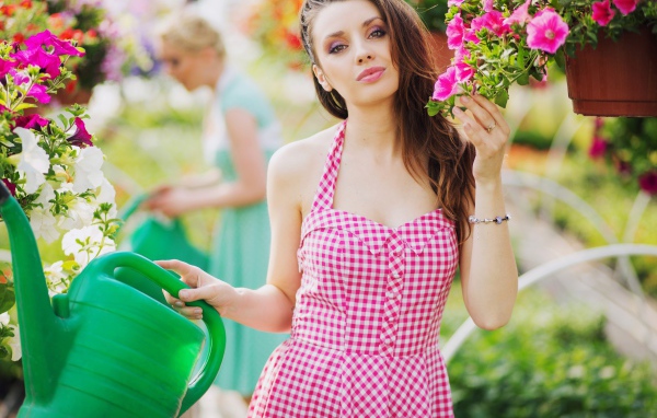 Красивая девушка с лейкой поливает цветы