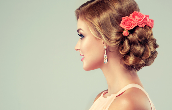 Красивая свадебная прическа у молодой девушки на сером фоне 