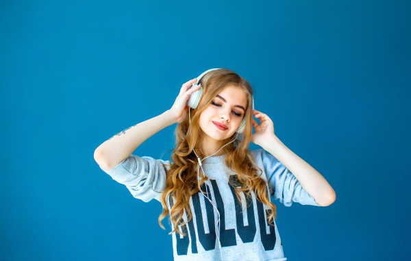 Красивая молодая девушка в наушниках на голубом фоне