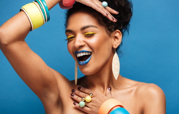 Красивая молодая девушка с ярким разноцветным макияжем на голубом фоне