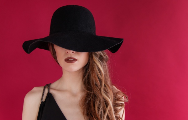 Большая черная шляпа закрывает лицо девушки