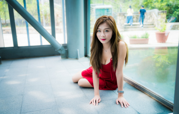 Голубоглазая девушка азиатка в красном платье на полу 