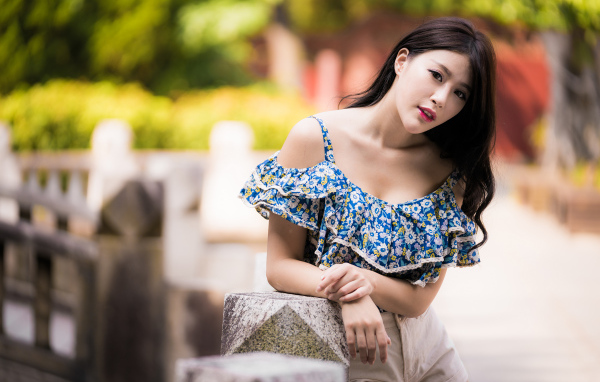 Кареглазая азиатка в яркой кофте в парке 