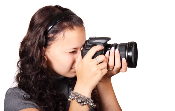 Молодая девушка шатенка с фотоаппаратом в руках на белом фоне