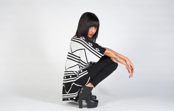 Брюнетка сидит на корточках 