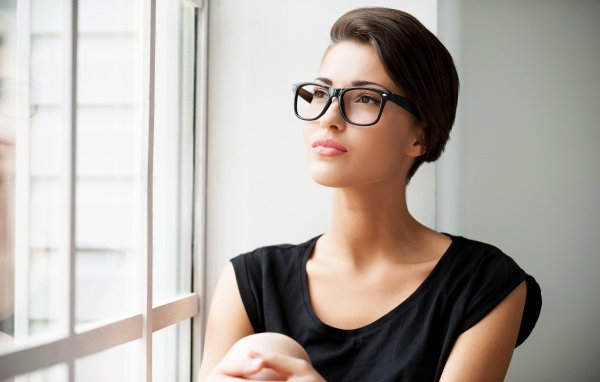 Деловая девушка в очках сидит у окна 