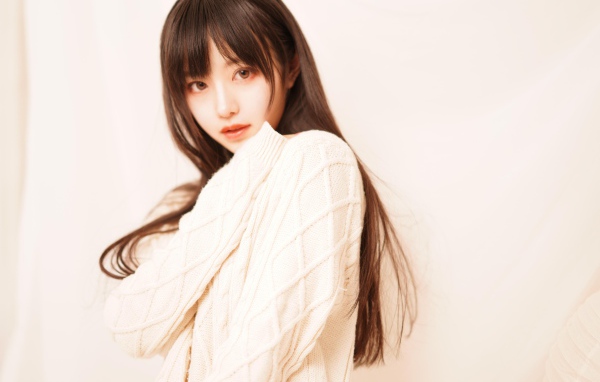 Милая азиатка в белом свитере на розовом фоне