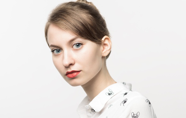 Милая голубоглазая девушка в рубашке на сером фоне