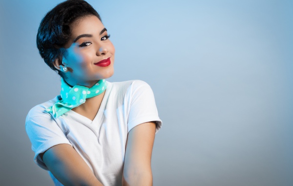 Милая улыбающаяся девушка с шарфом на шее на сером фоне