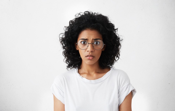 Темноволосая девушка в белой футболке на сером фоне