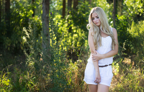 Нежная блондинка в белом костюме в лесу
