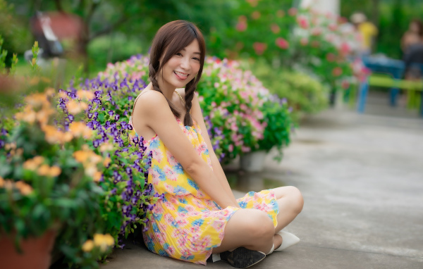 Смешная девушка азиатка в платье сидит на земле