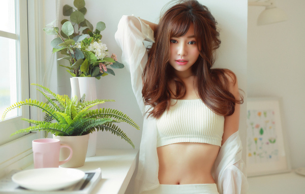 Нежная девушка азиатка стоит у окна