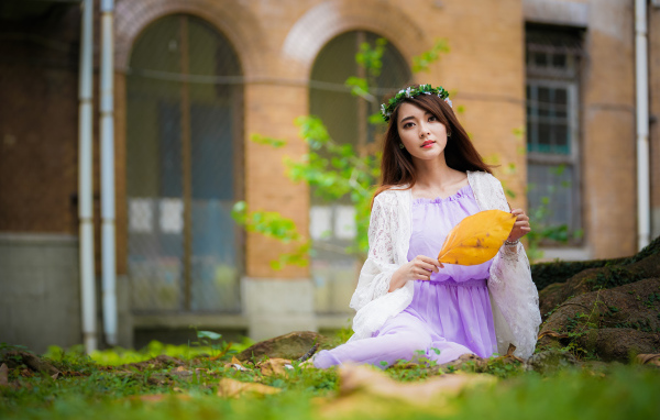 Девушка в красивом платье сидит на траве 