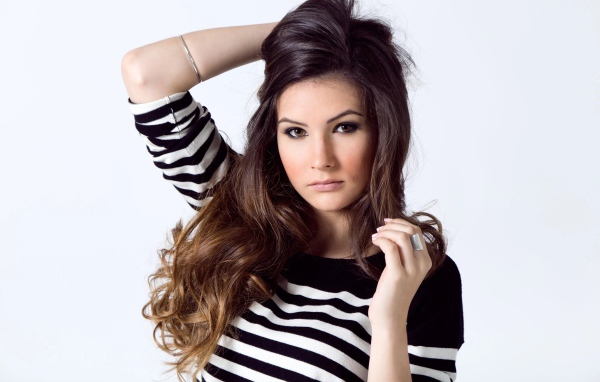 Девушка в полосатом свитере с рукой в волосах на белом фоне