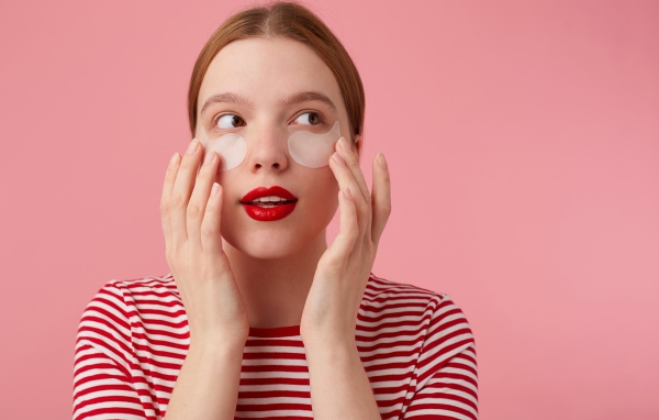 Девушка приклеивает патчи для глаз на лицо 