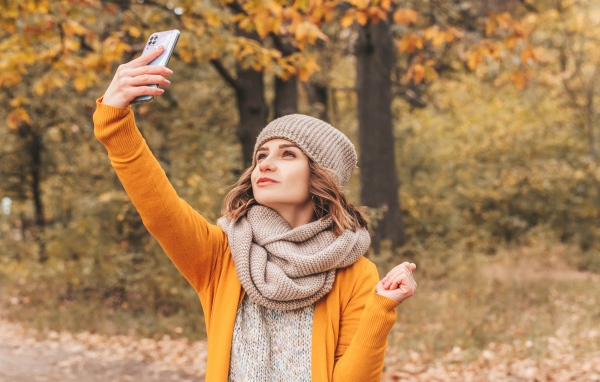 Девушка делает селфи на улице осенью 