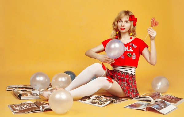 Девушка с шариками и журналами сидит на полу