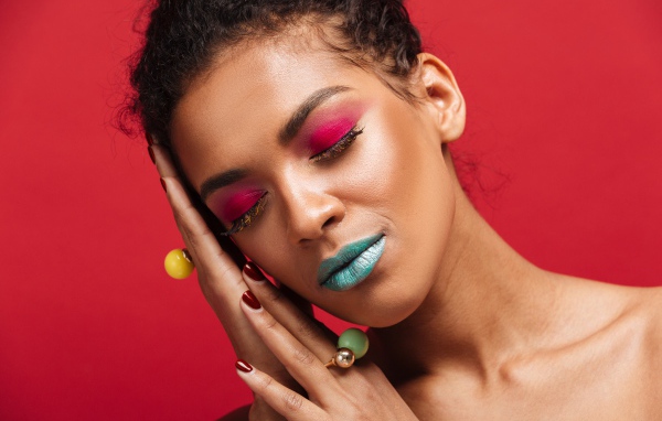 Девушка с ярким макияжем на красном фоне