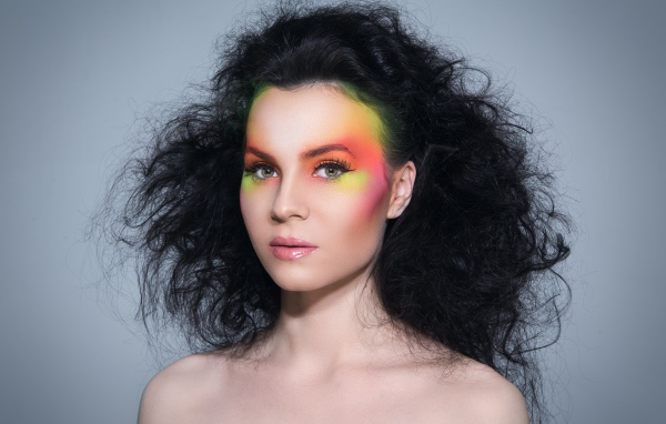 Девушка с начесом на волосах с ярким макияжем на сером фоне