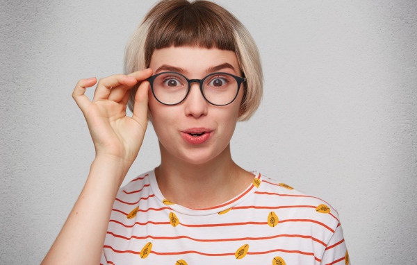 Девушка с короткой стрижкой поправляет очки 