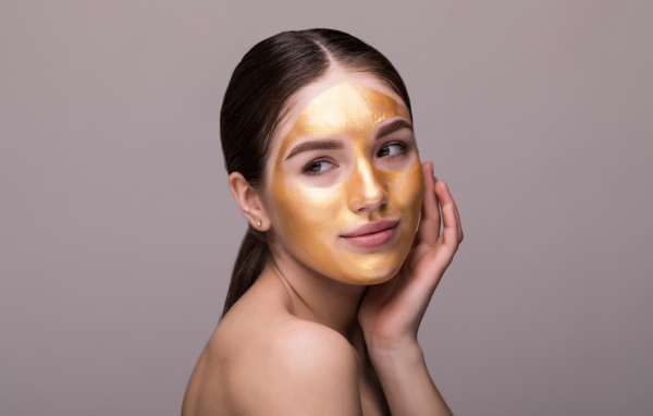 Золотая маска на лице у молодой девушки 