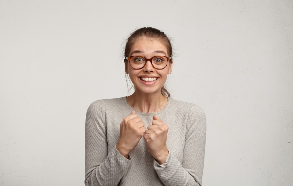 Радостная девушка в очках для зрения на сером фоне 