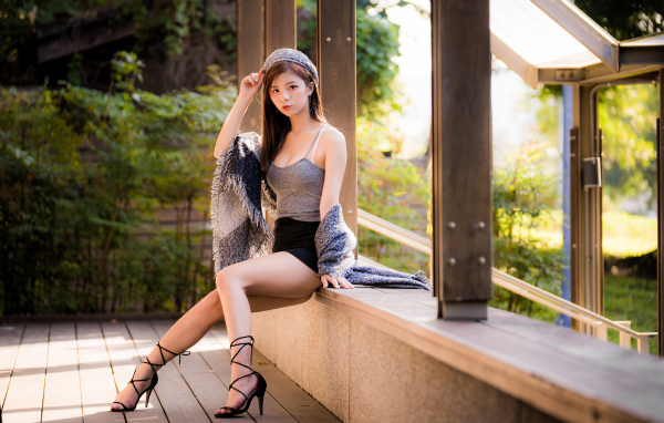 Длинноногая азиатка сидит на окне 