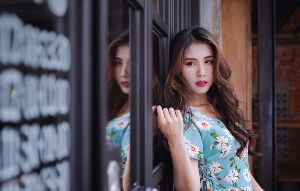 Длинноволосая девушка азиатка стоит у окна