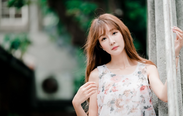 Длинноволосая азиатка стоит у стены 