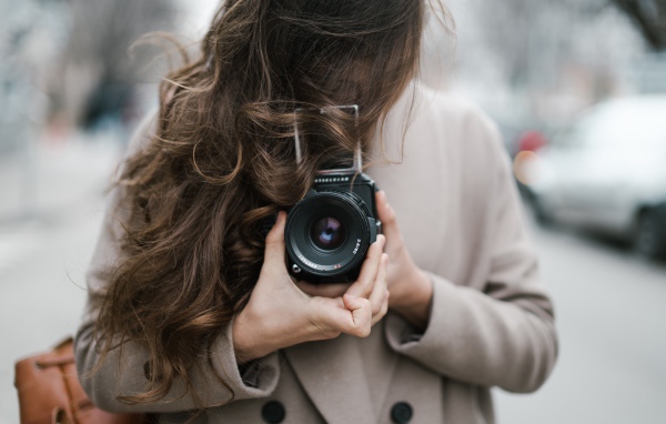 Длинноволосая девушка с фотоаппаратом в руках 