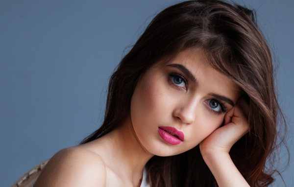Милая девушка с розовыми губами на сером фоне