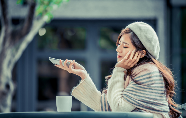 Мечтательная девушка с телефоном сидит в кафе 