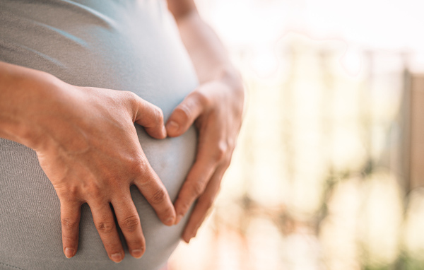 Беременная женщина держит руки на животе 